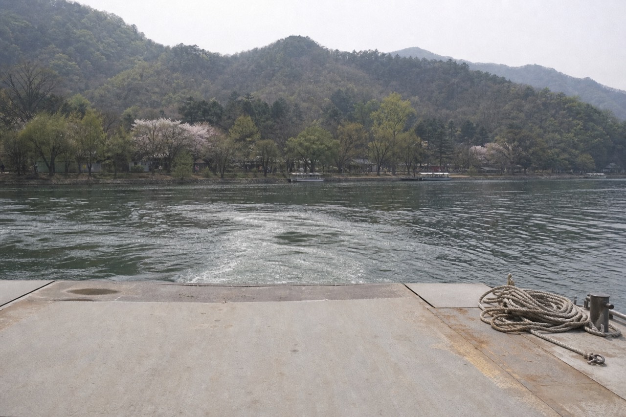 Ferry wharf on the North Han River near Nami Island with wooded hills behind, no text, no logos, no people.
